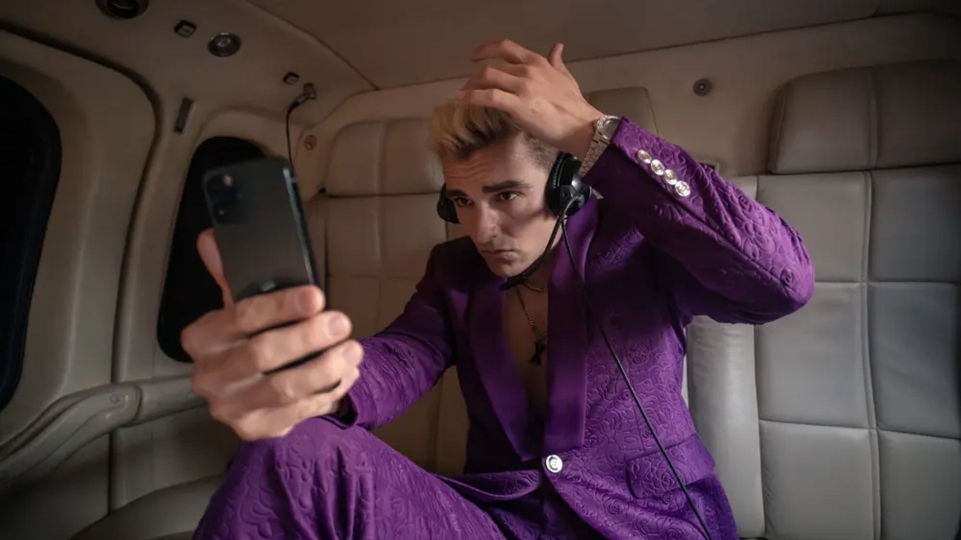 Dave Franco in a purple suit looking at his phone, scene from The Afterparty series
