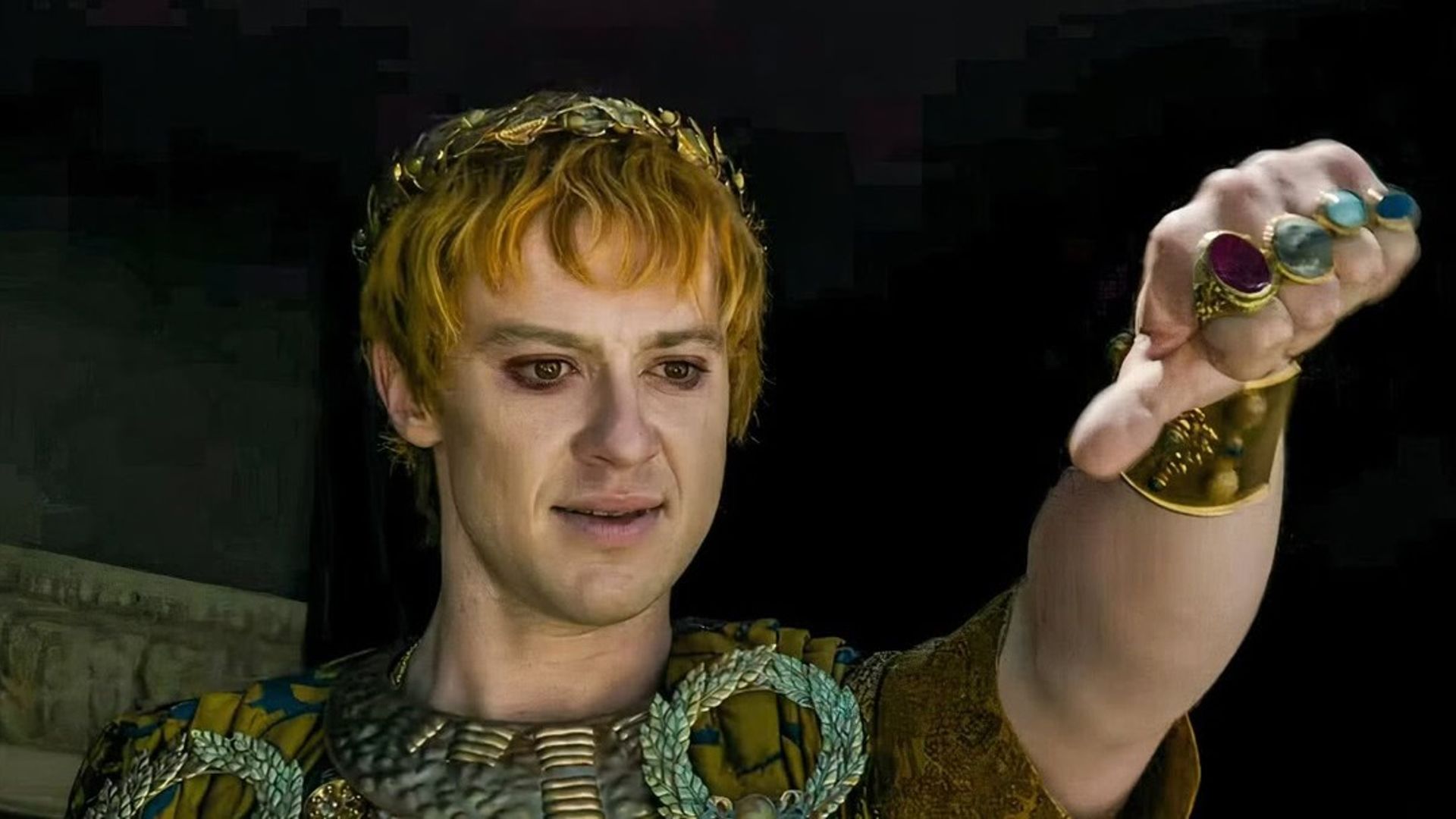 Joseph Quinn in Roman emperor makeup and costume showing a thumbs down gesture