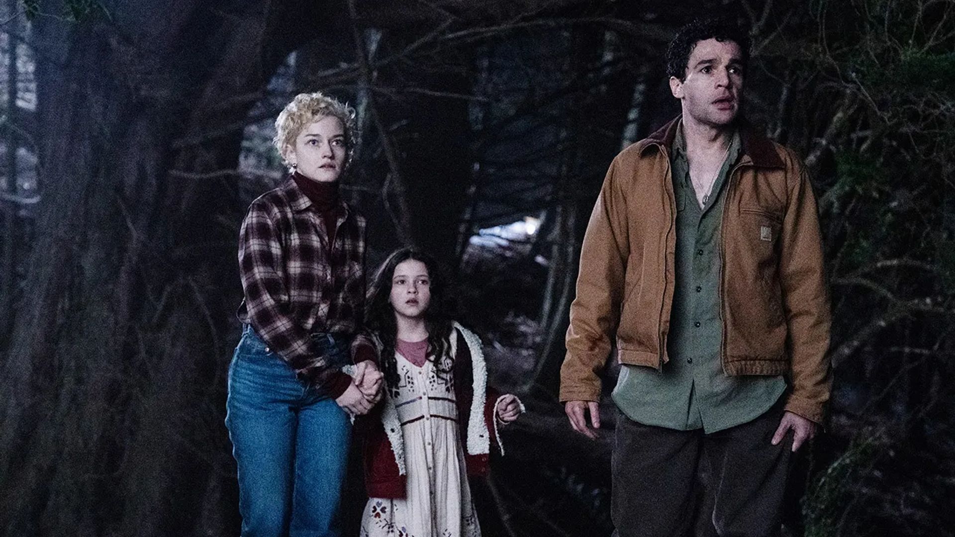 Julia Garner, Christopher Abbott and Matilda Firth in a nighttime forest, still from the film "Wolf Man"