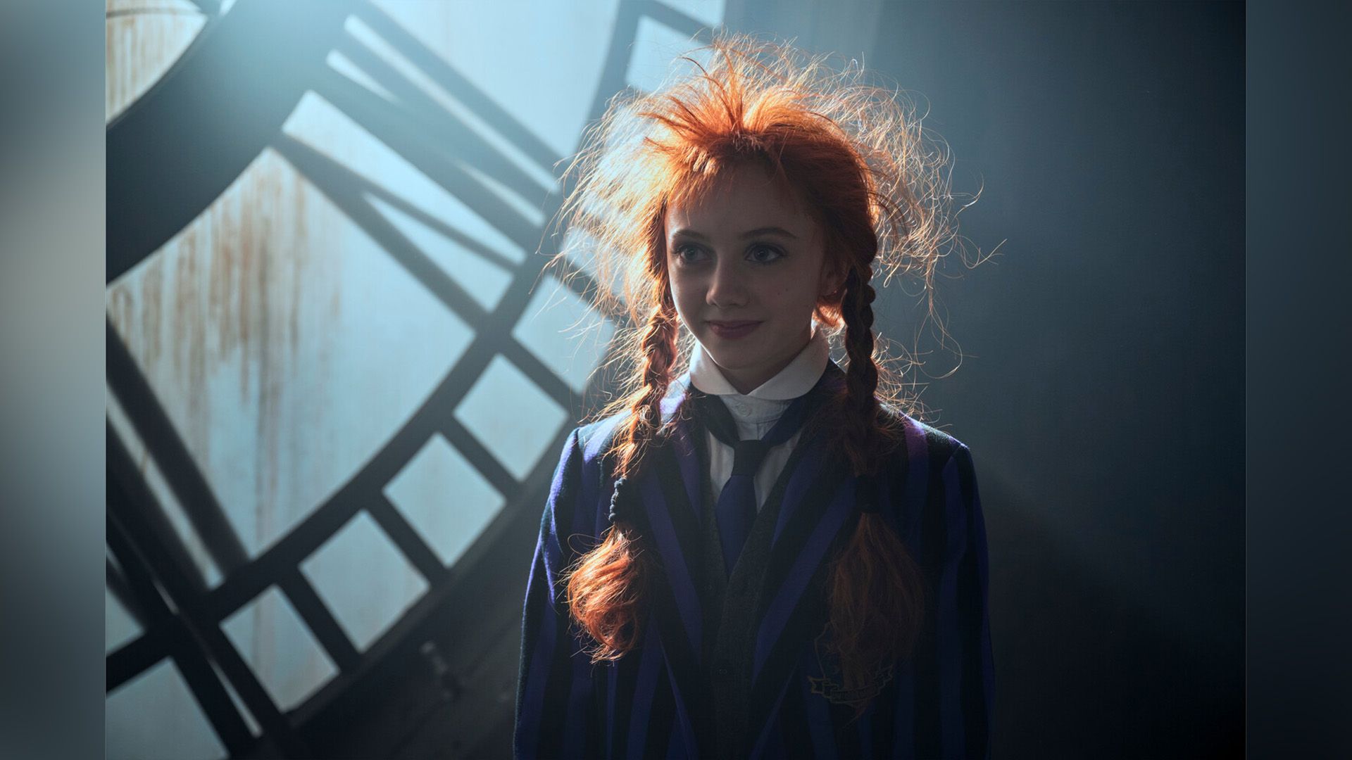 Evie Templeton with red braids and tousled hair, wearing a black and purple striped blazer