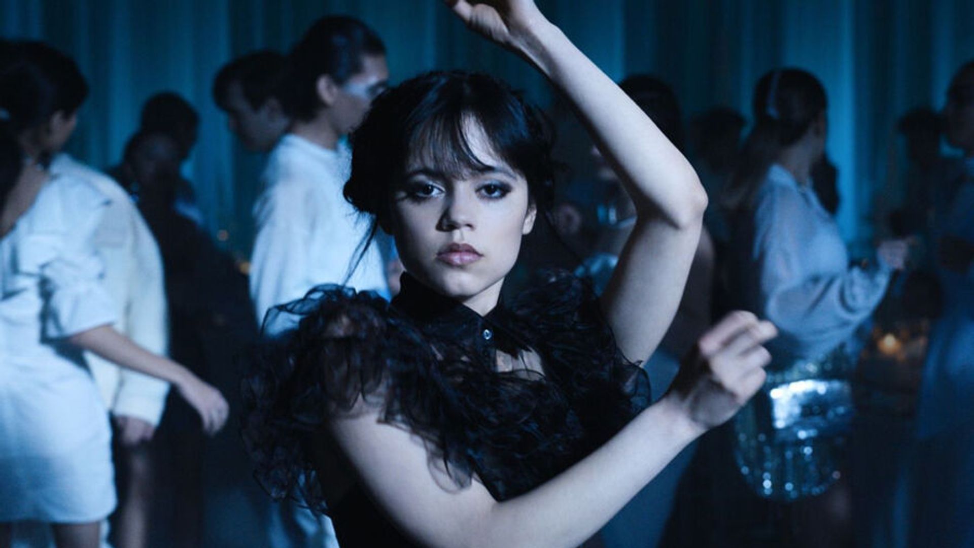 Jenna Ortega dances in a black dress making angular arm movements