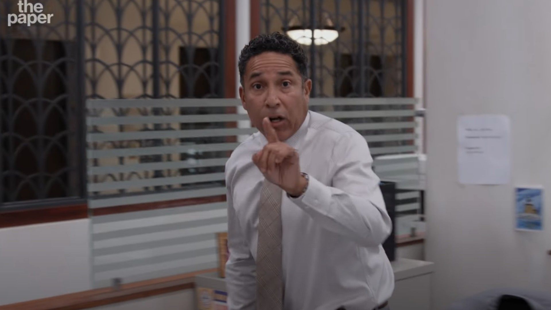Oscar Nunez in a white shirt pointing his index finger at the camera