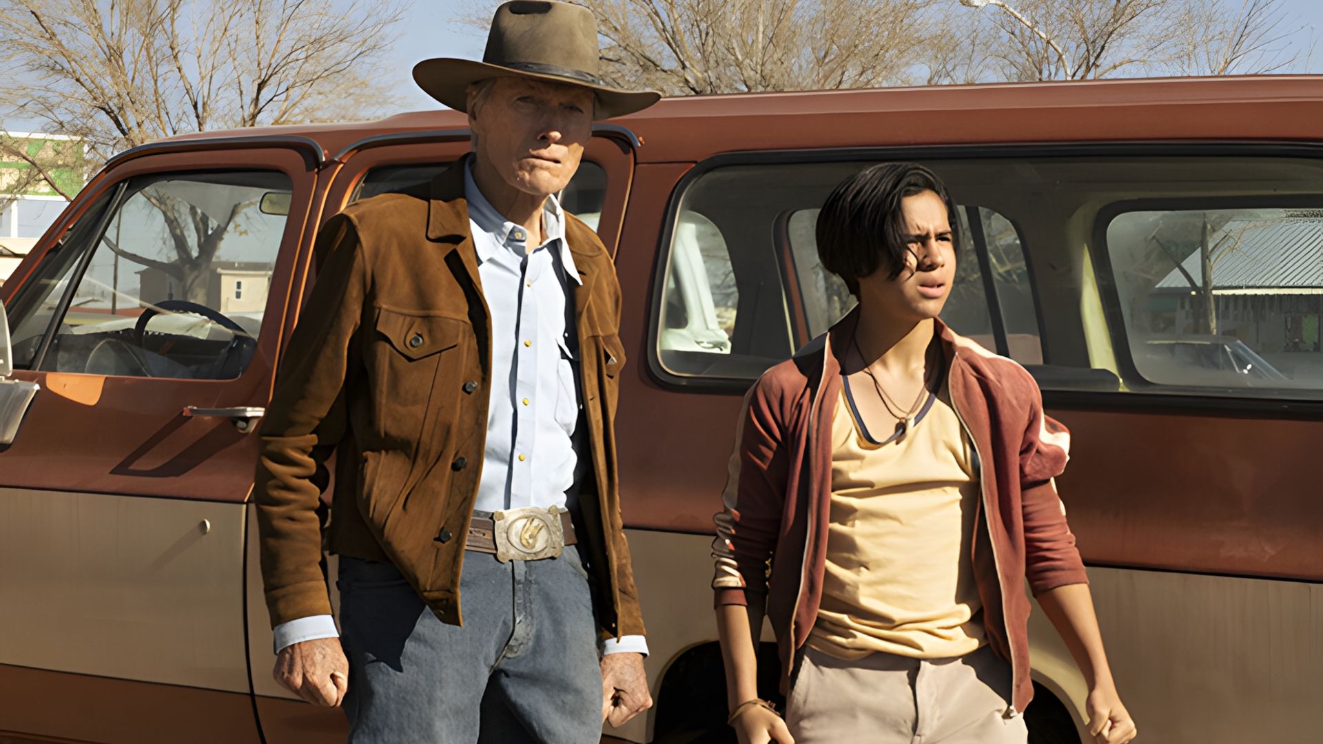 Clint Eastwood and Eduardo Minett stand next to a pickup truck against a sunny street backdrop