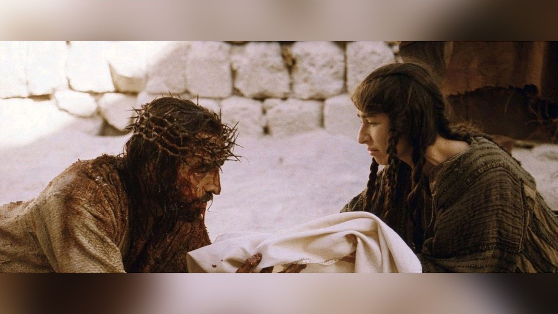 Sabrina Impacciatore offers a veil to the bloodied Jesus wearing a crown of thorns