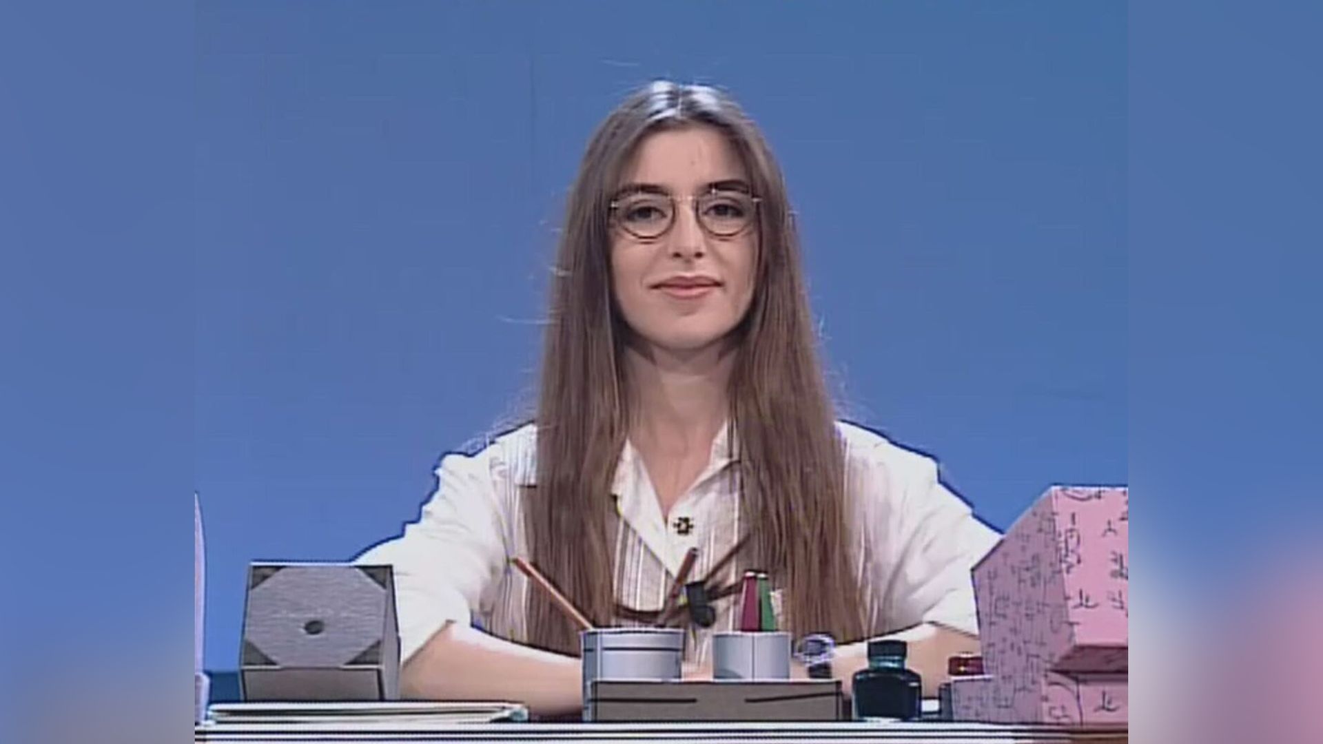 Young Sabrina Impacciatore in glasses and a white blouse sits at a desk