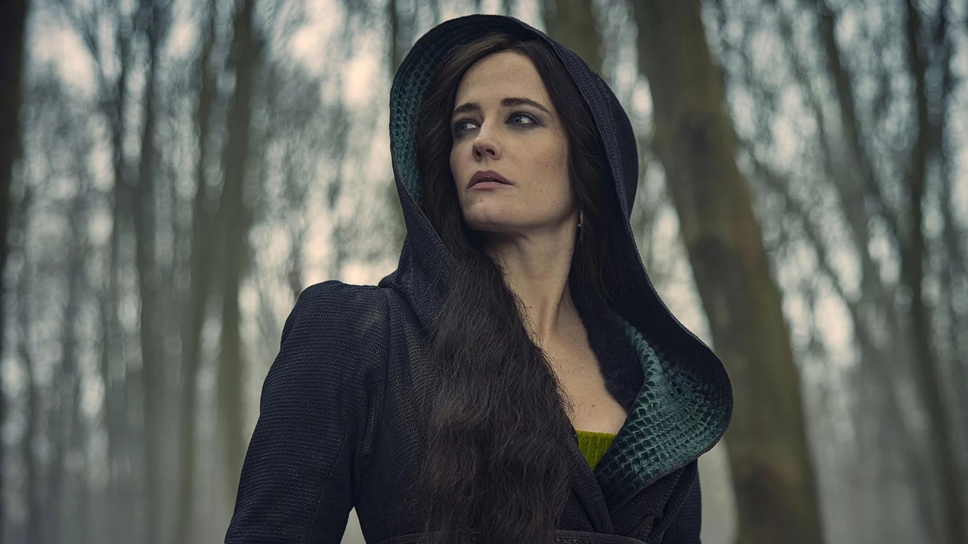 Eva Green in a black hooded dress against a winter forest backdrop