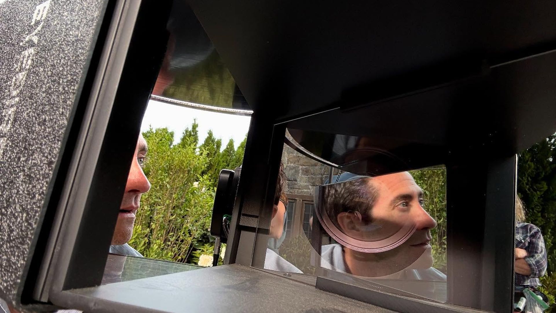 Jake Gyllenhaal looks into equipment with mirrors and lenses, his face reflected in the optical surfaces
