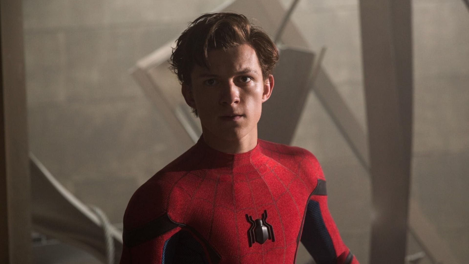 Actor Tom Holland in red superhero costume with spider emblem on chest