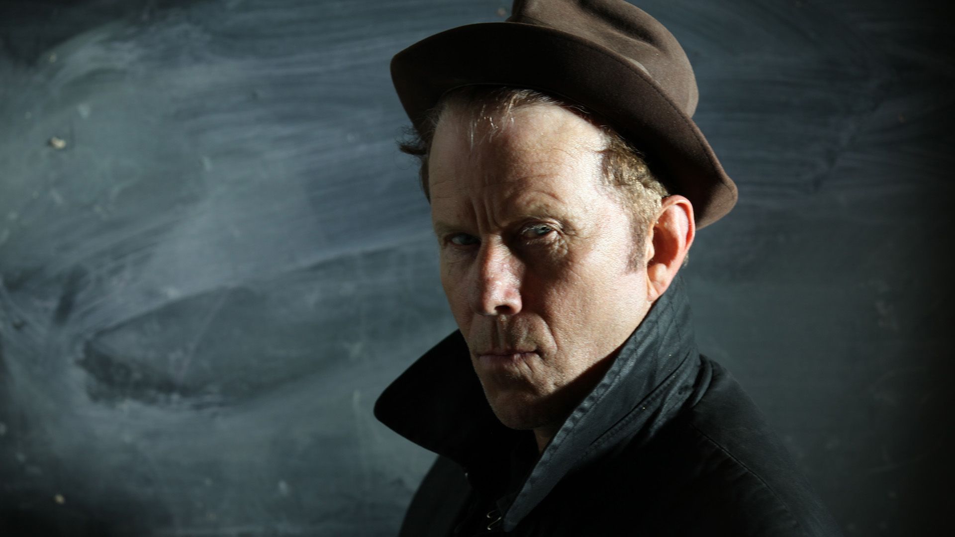Musician Tom Waits in a hat and coat with upturned collar