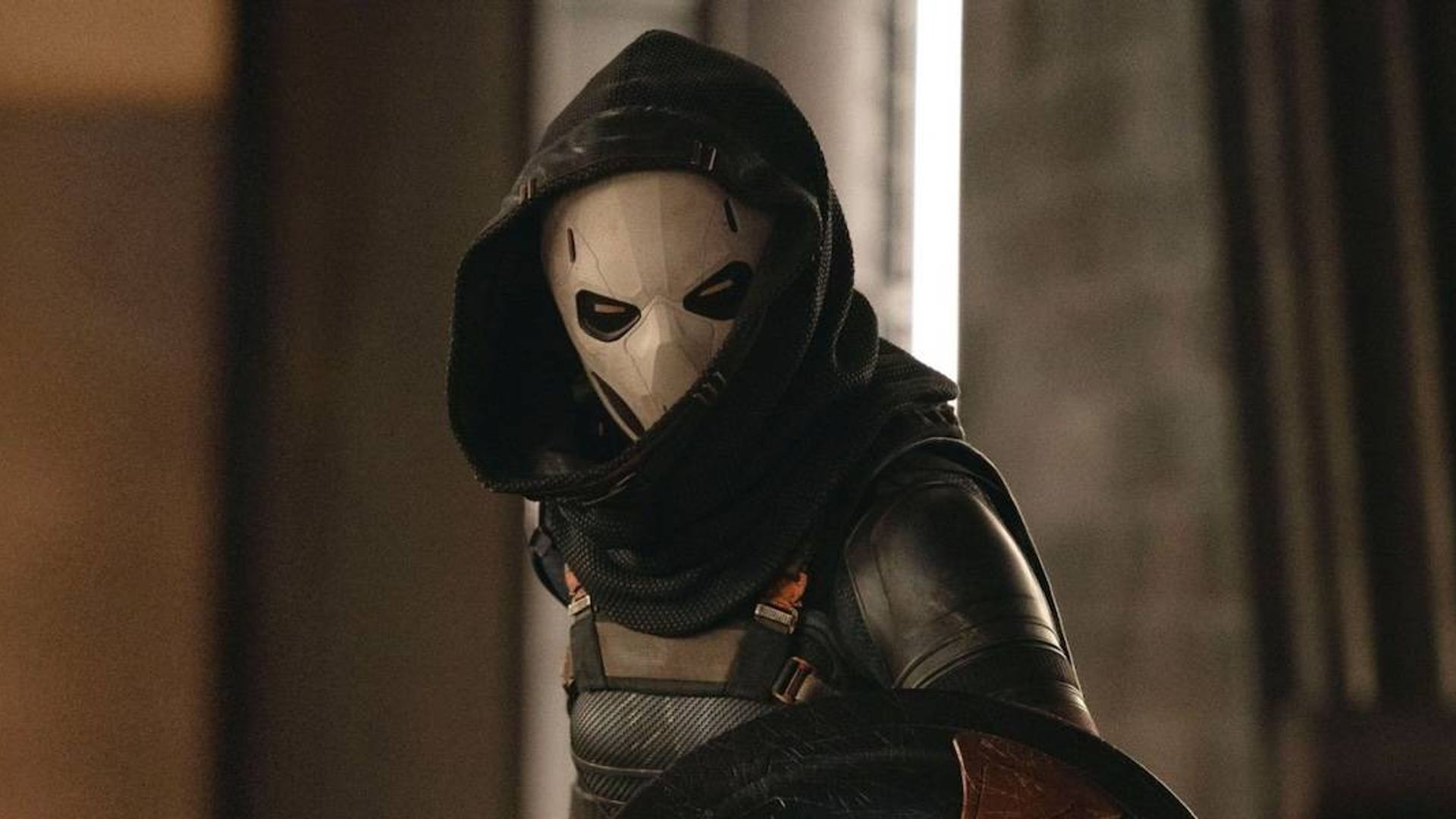 Olga Kurylenko in a white mask completely covering her face and a hood