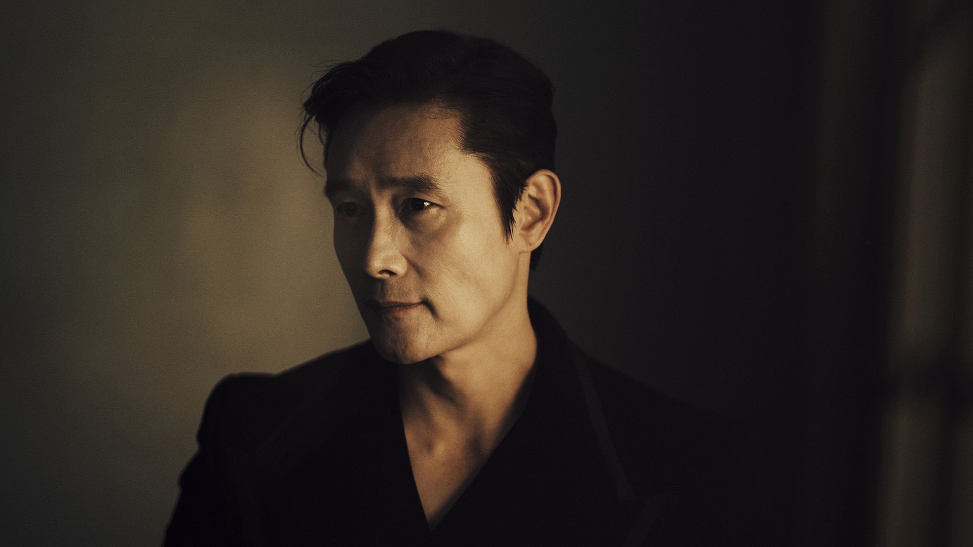 Actor Lee Byung-hun in half-profile in dim lighting