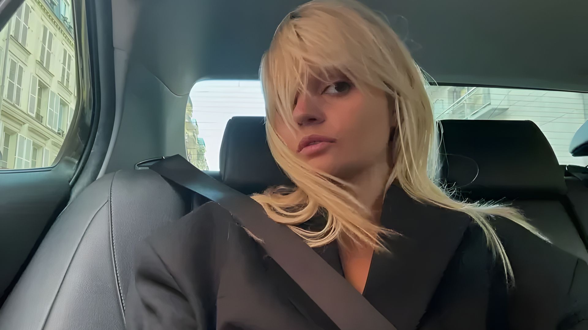 Blonde with a bob haircut in the passenger seat of a car
