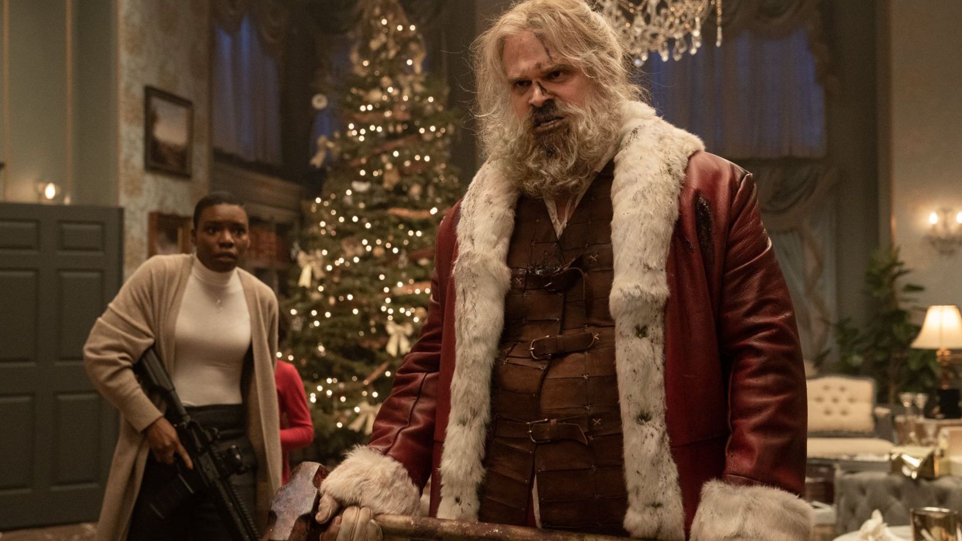 David Harbour in Santa costume holding an axe, with Christmas interior in the background