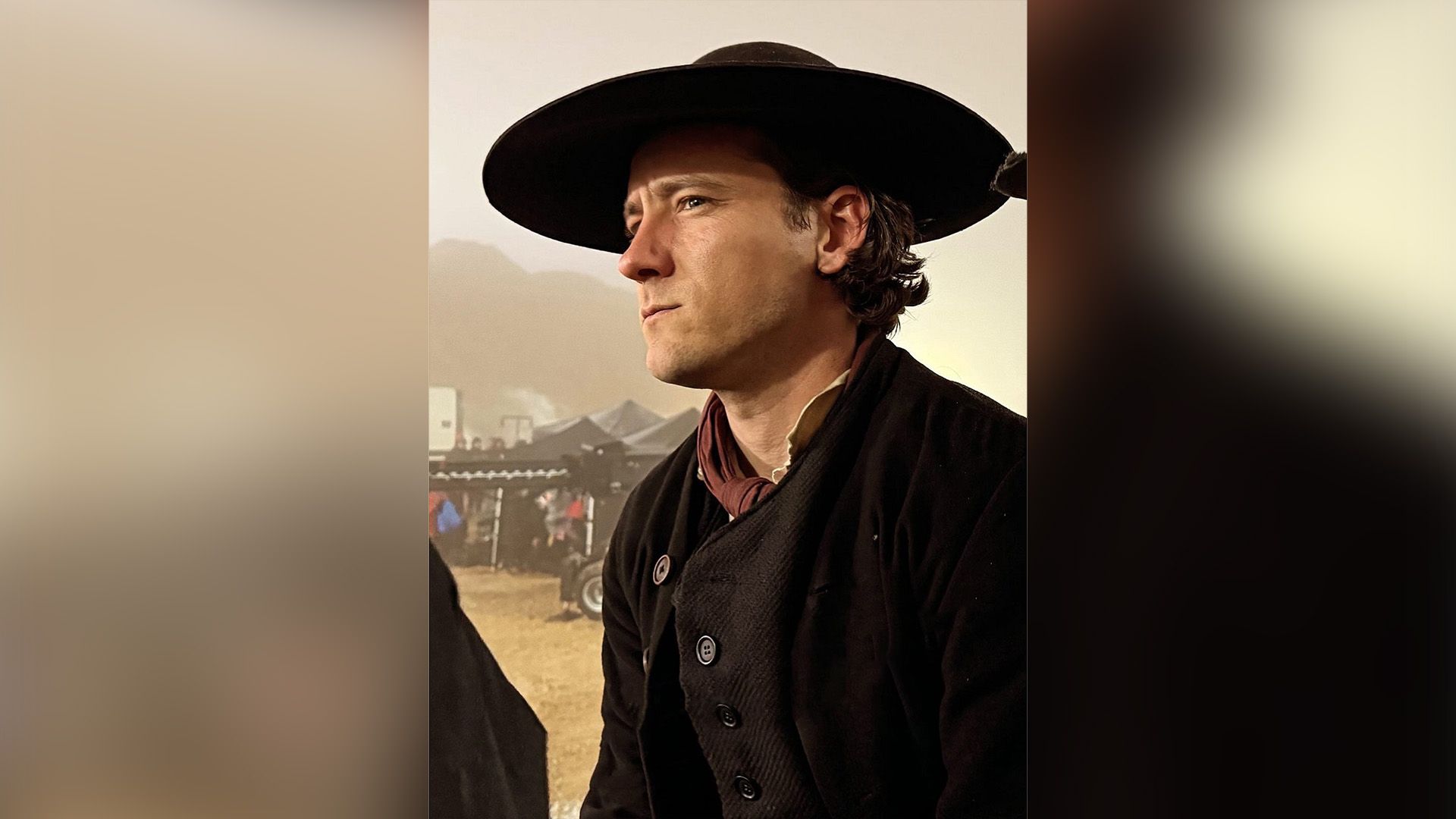 Lewis Pullman in a black wool jacket and black wide-brimmed hat