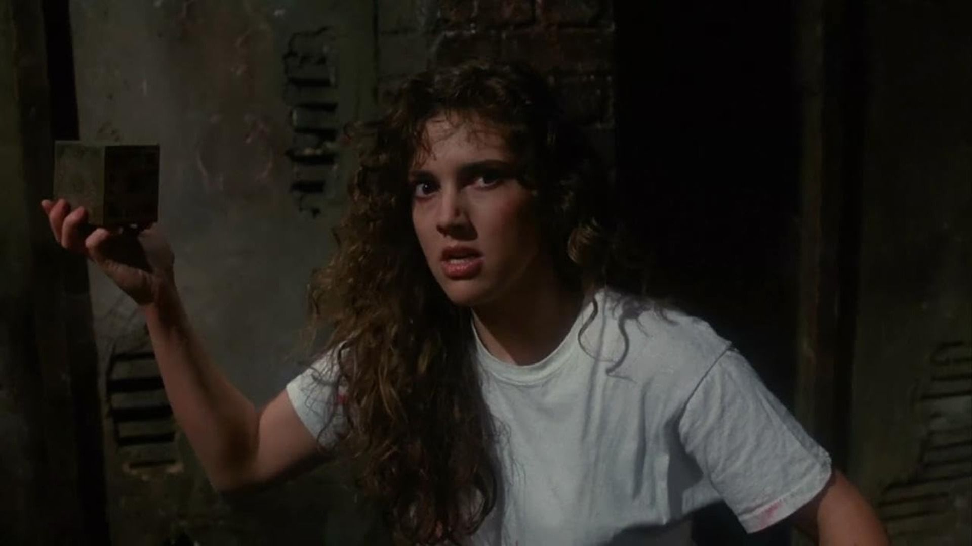 A girl in a white t-shirt is holding a golden jewelry box in her hands