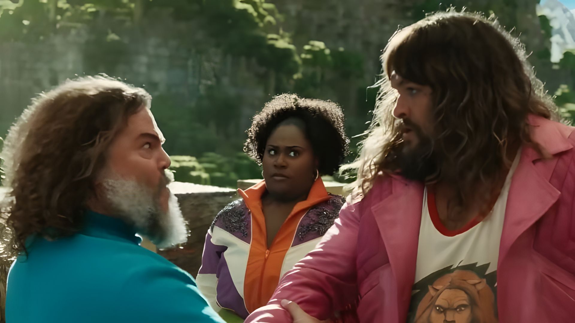 Jack Black in a blue t-shirt and Jason Momoa in a pink jacket vigorously shaking hands