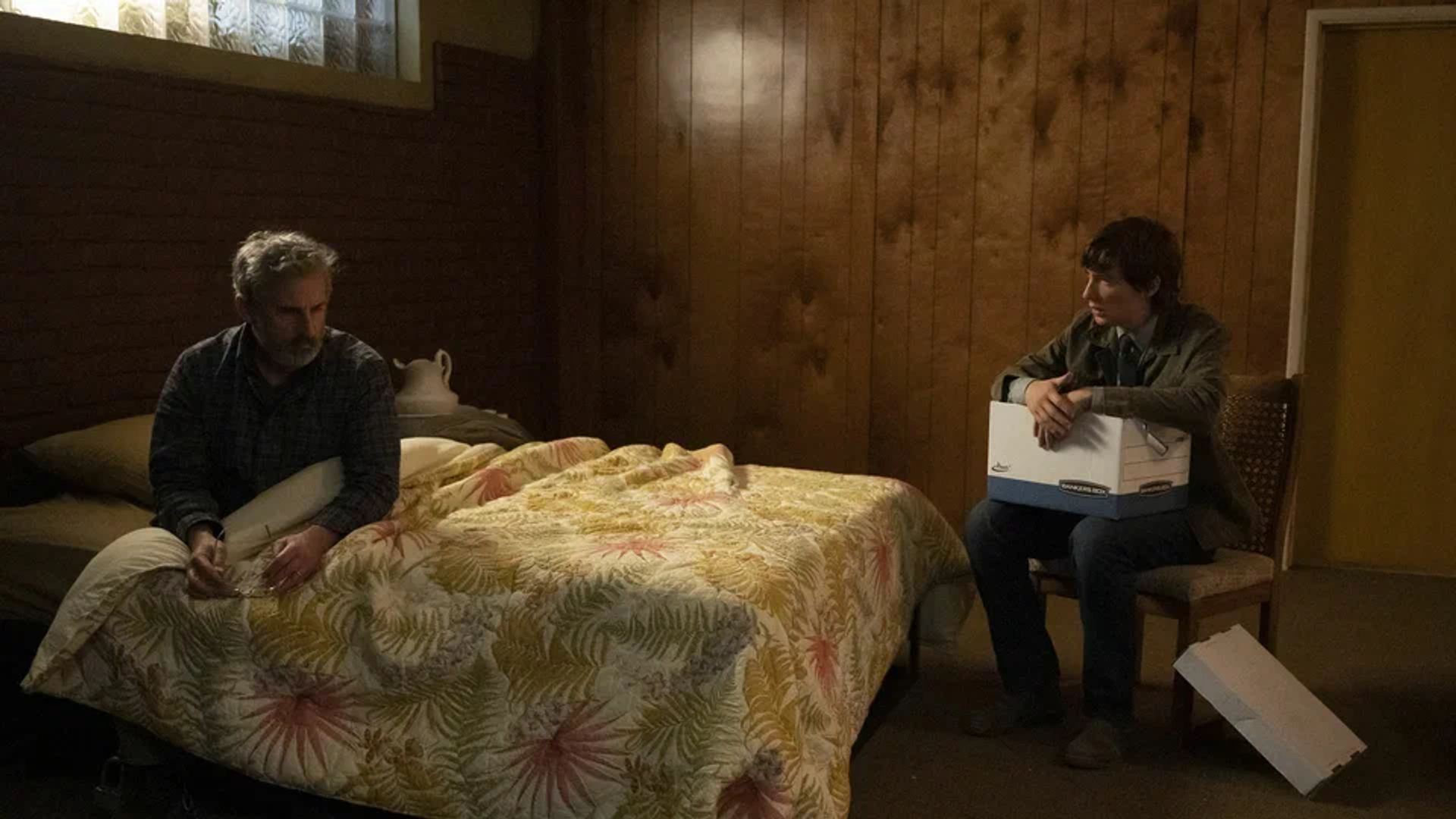 Steve Carell lying on a bed with Domhnall Gleeson sitting on a chair across from him