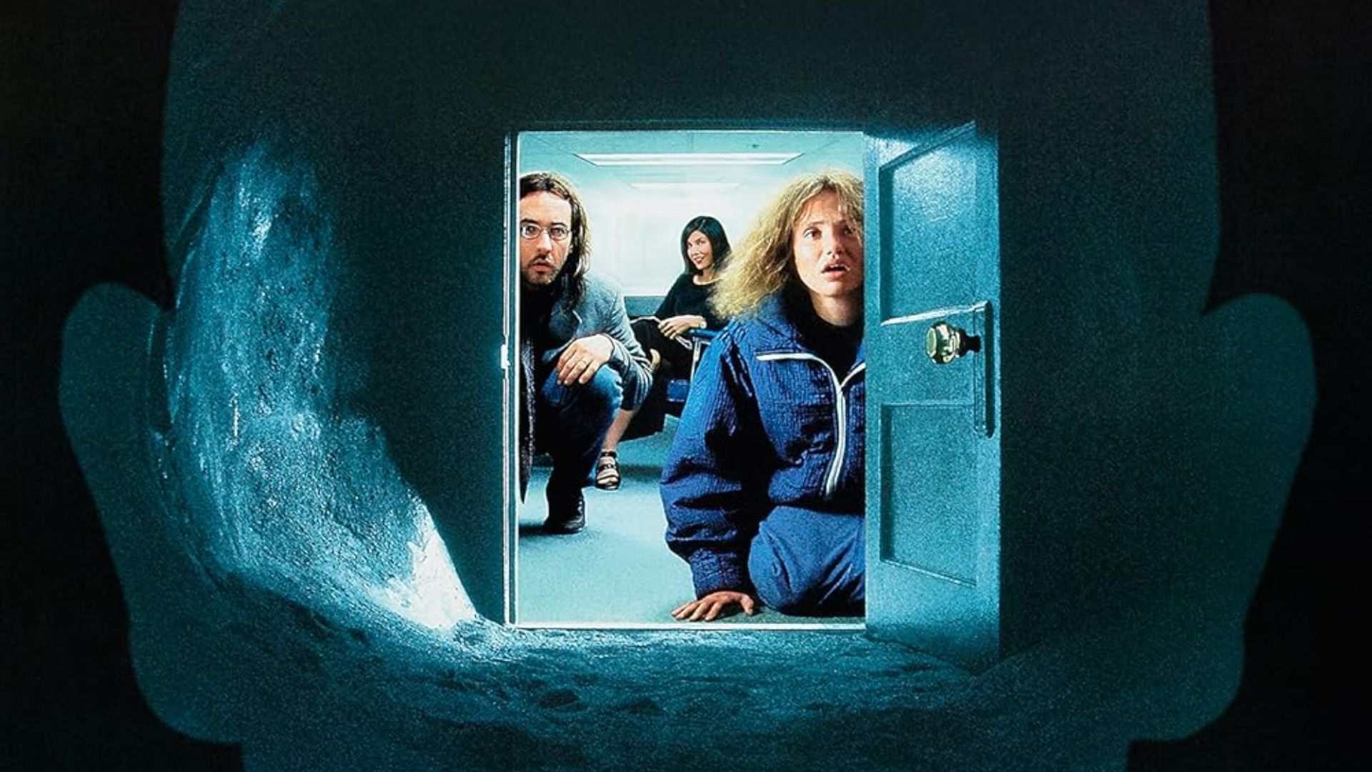 A man and two women sit in front of a small door and look inside