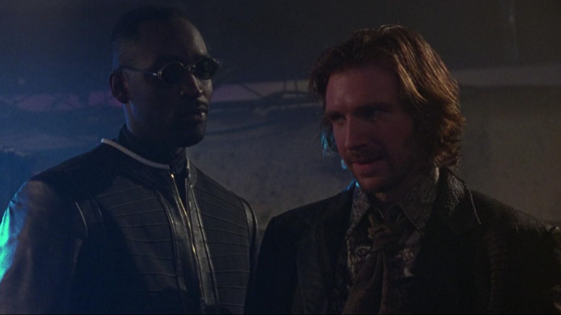 Two men stand in old-fashioned clothing and smile