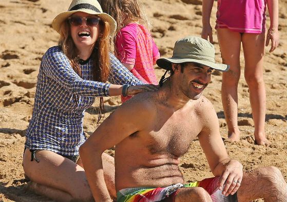 Isla Fisher with her husband on a beach